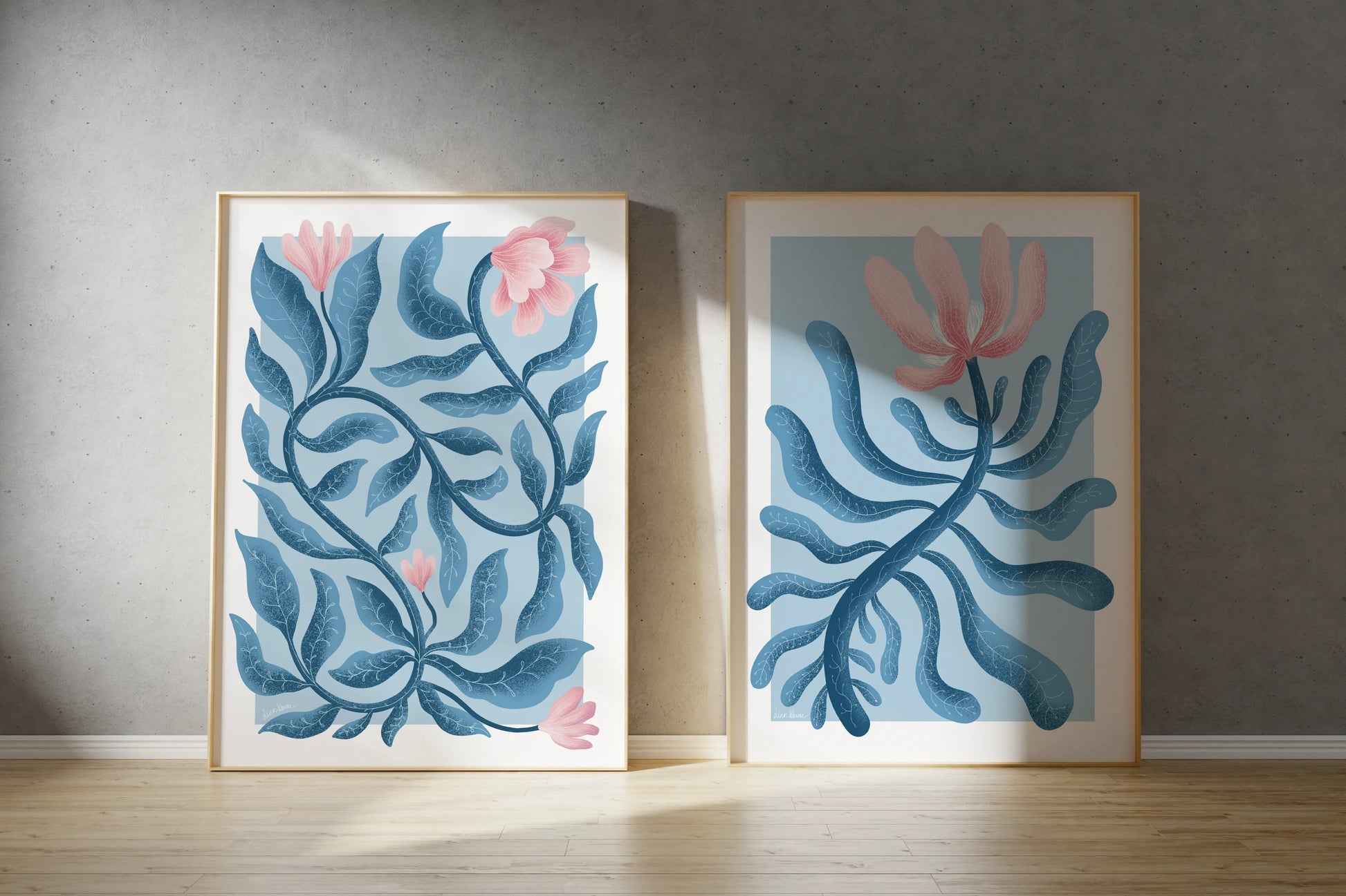 Two framed artworks with blue and pink floral designs on a gray wall.